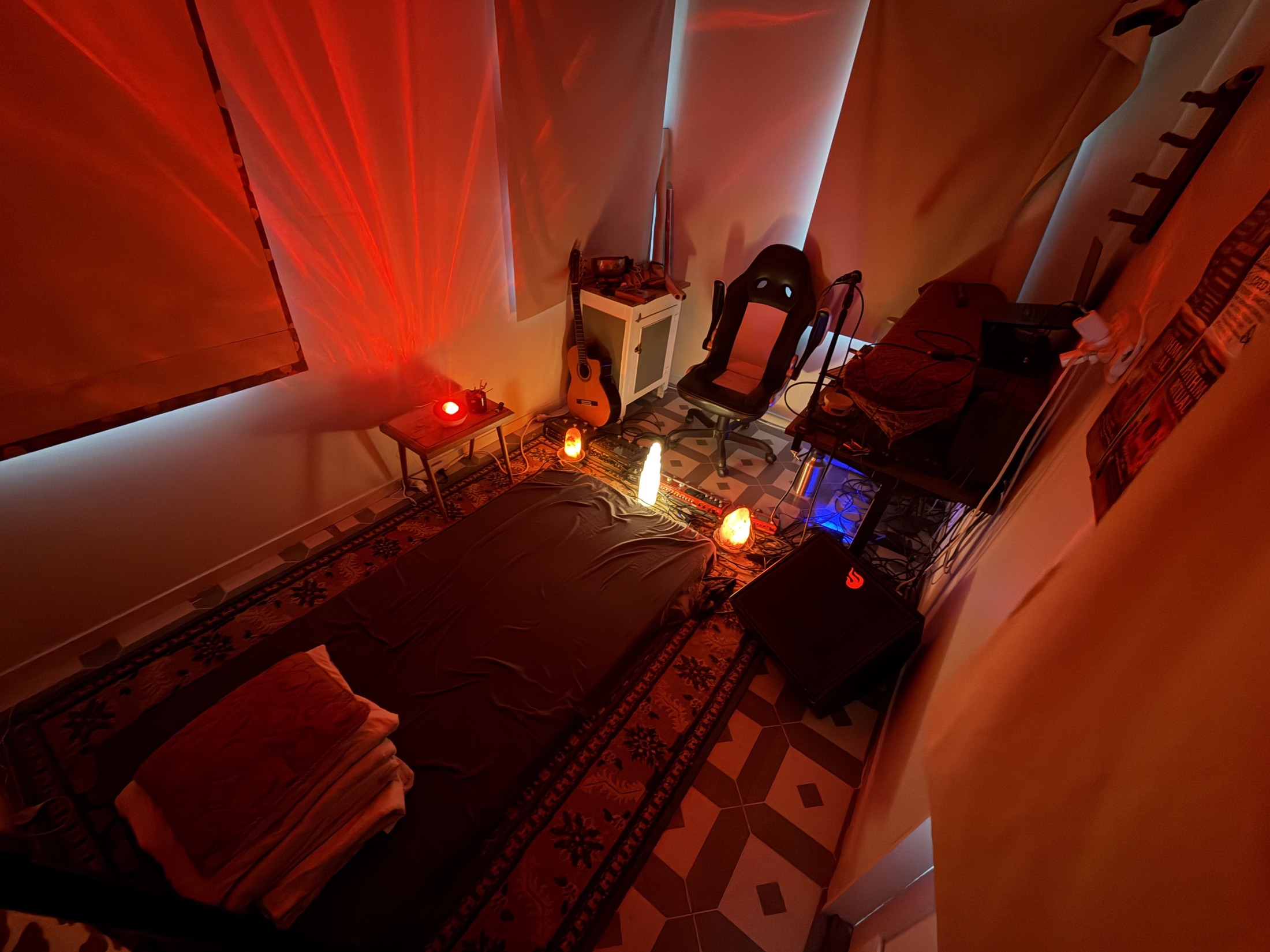 A warm, candlelit sound healing room with instruments arranged around a treatment mat.